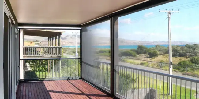 Coastal balcony with Ziptrak® outdoor blinds providing wind shade protection and ocean views