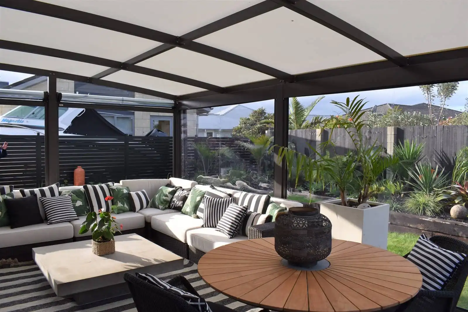 Modern outdoor pergola curved canopy with Ziptrak® clear PVC blinds enclosing a stylish lounge seating area - Rainbow Shade