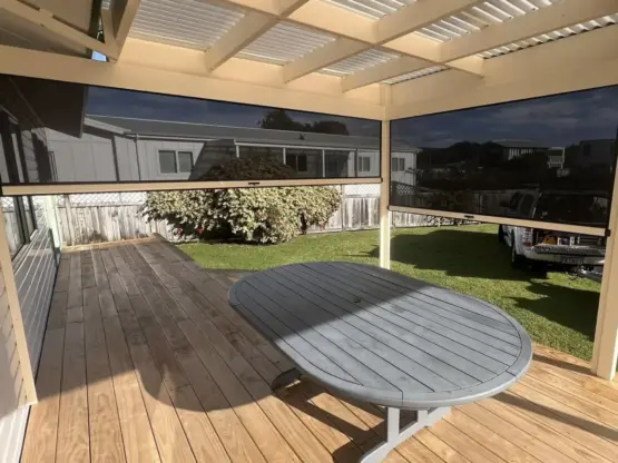 Outdoor entertaining area with partially lowered outdoor living blinds, showcasing mesh outdoor blinds in Visiontex® Plus 94 Carbon Black with Ziptrak® off White blinds system, practical outdoor screens by Rainbow Shade NZ