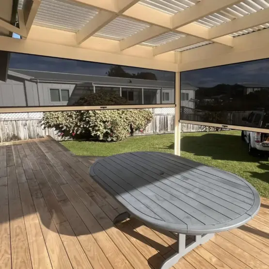 Outdoor entertaining area with partially lowered outdoor living blinds, showcasing mesh outdoor blinds in Visiontex® Plus 94 Carbon Black with Ziptrak® off White blinds system, practical outdoor screens by Rainbow Shade NZ