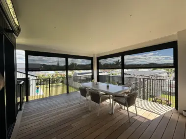 Outdoor entertaining deck with outdoor living blinds lowered for shade, showcasing mesh outdoor blinds in Visiontex® Plus 94 and Ziptrak® blinds system from Rainbow Shade NZ and Covered, enhancing outdoor blinds NZ functionality
