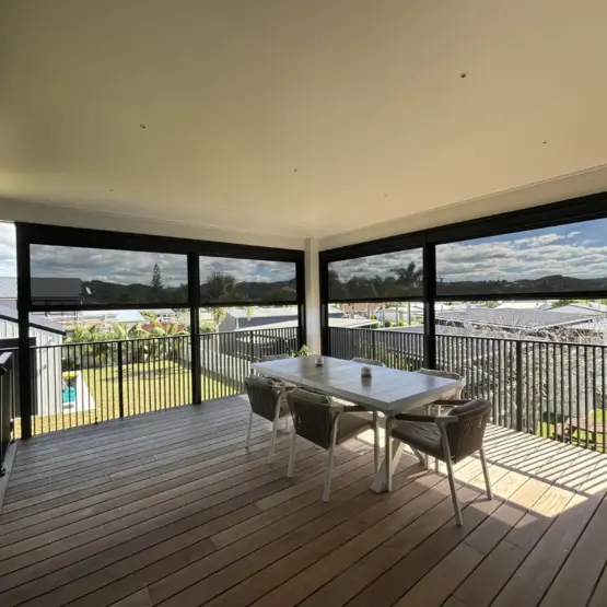 Outdoor entertaining deck with outdoor living blinds lowered for shade, showcasing mesh outdoor blinds in Visiontex® Plus 94 and Ziptrak® blinds system from Rainbow Shade NZ and Covered, enhancing outdoor blinds NZ functionality