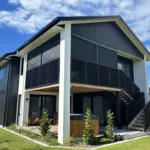 Corner perspective of elevated deck with outdoor living blinds in use, showing mesh outdoor blinds in Visiontex® Plus 94 with Ziptrak® blinds, a durable outdoor blinds NZ solution from Covered & Rainbow Shade NZ