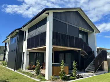 Corner perspective of elevated deck with outdoor living blinds in use, showing mesh outdoor blinds in Visiontex® Plus 94 with Ziptrak® blinds, a durable outdoor blinds NZ solution from Covered & Rainbow Shade NZ
