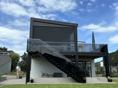 Contemporary home with elevated outdoor area fitted with outdoor living blinds, featuring mesh outdoor blinds in Visiontex® Plus 94 with Ziptrak® blinds system, high-quality outdoor blinds by Covered & Rainbow Shade NZ