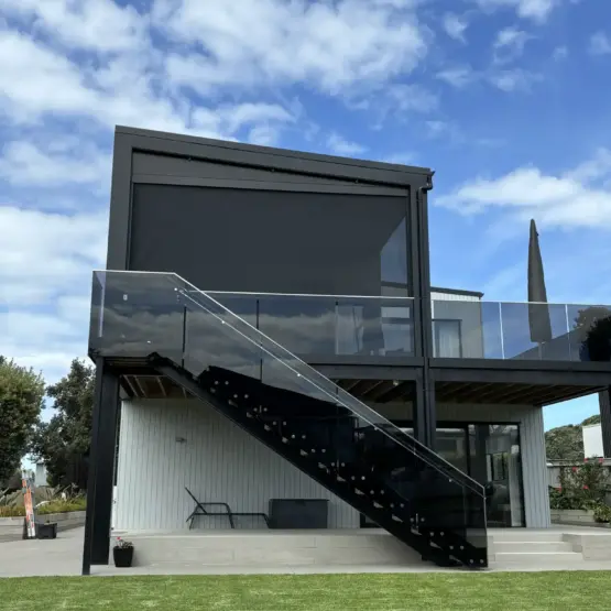 Contemporary home with elevated outdoor area fitted with outdoor living blinds, featuring mesh outdoor blinds in Visiontex® Plus 94 with Ziptrak® blinds system, high-quality outdoor blinds by Covered & Rainbow Shade NZ