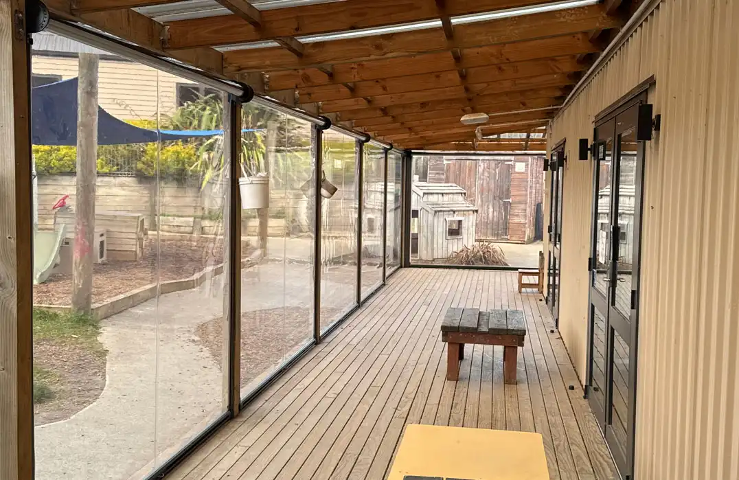 Ziptrak PVC Clear outdoor blinds installed on a covered timber deck at Country Village Kindergarten Paerata, creating an all-weather protected outdoor learning and play area